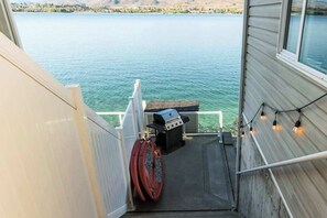 A deck area with a grill and a hot tub, overlooking a body of water. - Large 2BR Lakefront - Hot Tub - Dock - Patio (Chelan)