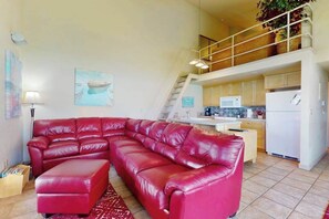 A spacious living area with a red leather sectional sofa, a kitchen with white appliances, and a staircase leading to an upper level. - Studio Lakefront 1st-floor - Patio - Pool (Chelan)