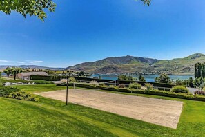 Una cancha de tenis con vista a un lago y montañas.