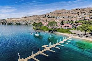 Una zona costera con un puerto deportivo, edificios y un paisaje montañoso.