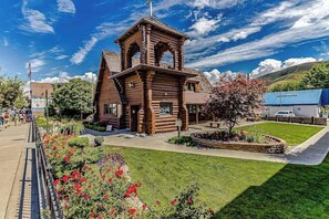 A wooden cabin-style building with a prominent tower, surrounded by well-maintained gardens and a clear sky. - 2BR lakeside condo with stunning views and grill (Chelan)