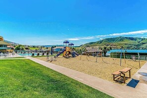 Ein Spielplatz mit Rutschen, Schaukeln, einem Picknicktisch und einem Poolbereich.