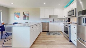 Een moderne keuken met witte kasten, roestvrijstalen apparatuur en een centraal eiland.