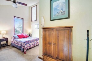 A bedroom with a bed, a wooden cabinet, a ceiling fan, and a framed picture on the wall. - 1BR Lakefront - Pool - Hot Tub - Balcony (Chelan)