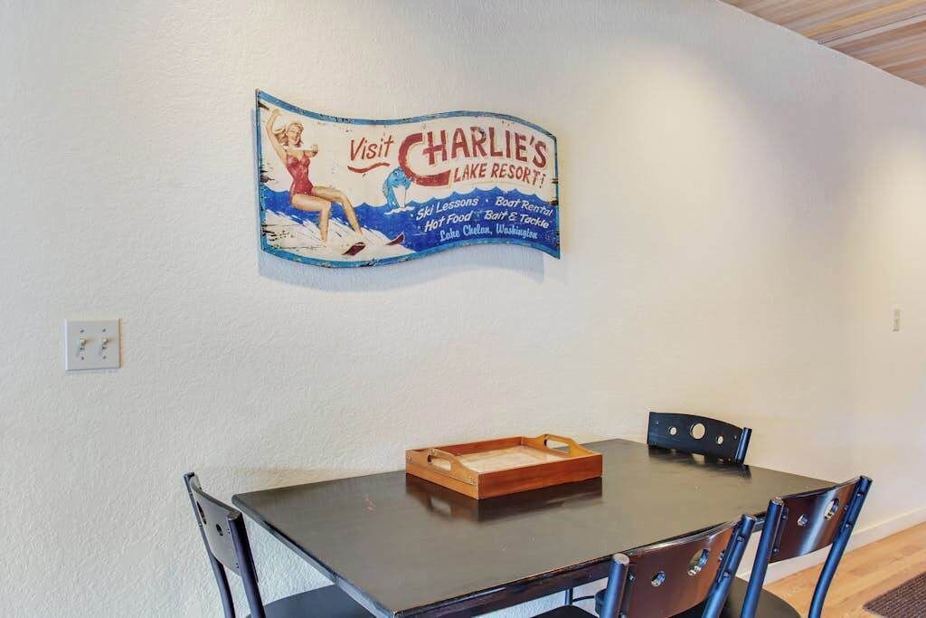 A dining area with a table and chairs, a placemat, and a wall-mounted sign advertising a lake resort.