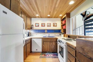 A kitchen with wooden cabinets, a white refrigerator, a stove, and a sink.