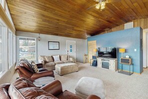 A living room with a wooden ceiling, a large TV, and a blue accent wall.