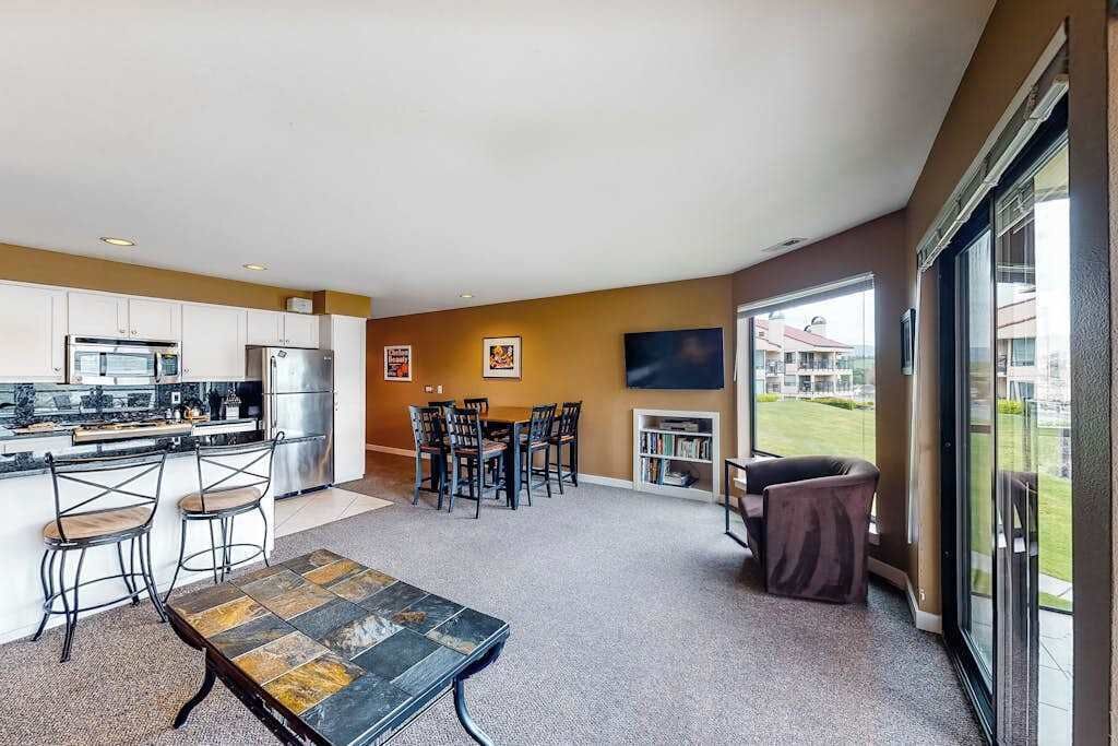 A modern kitchen with a dining area, a flat-screen TV, and a view of the outdoors.