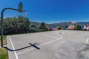 Ein Basketballplatz im Freien mit freiem Blick auf einen See und Berge im Hintergrund.