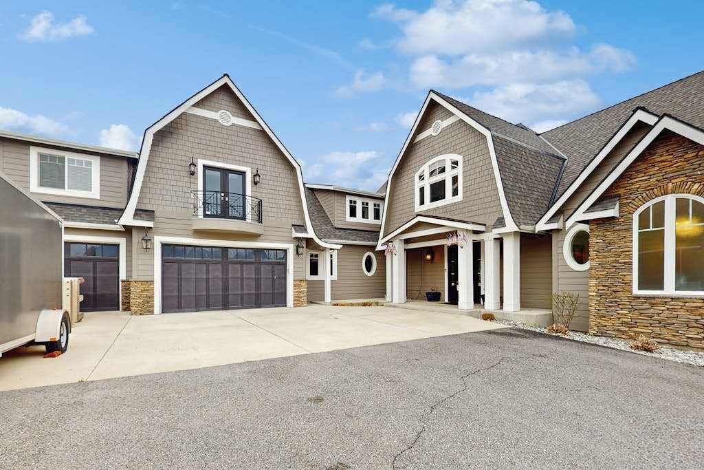 Un quartier résidentiel composé de plusieurs maisons, chacune dotée d’un garage, d’un porche à l’avant et d’une façade en pierre sur un de ses côtés.