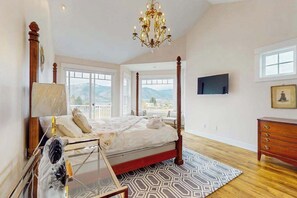 A bedroom with a four-poster bed, a chandelier, a television, and a view of the outdoors. - Luxury home - wine country - private pool, hot tub (Manson)