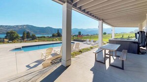 Ett takförsett utomhusområde med en pool, solstolar, ett picknickbord och en bubbelpool.