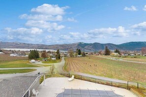 A view from a balcony overlooking a vineyard, a road, and distant mountains. - Luxury home - wine country - private pool, hot tub (Manson)