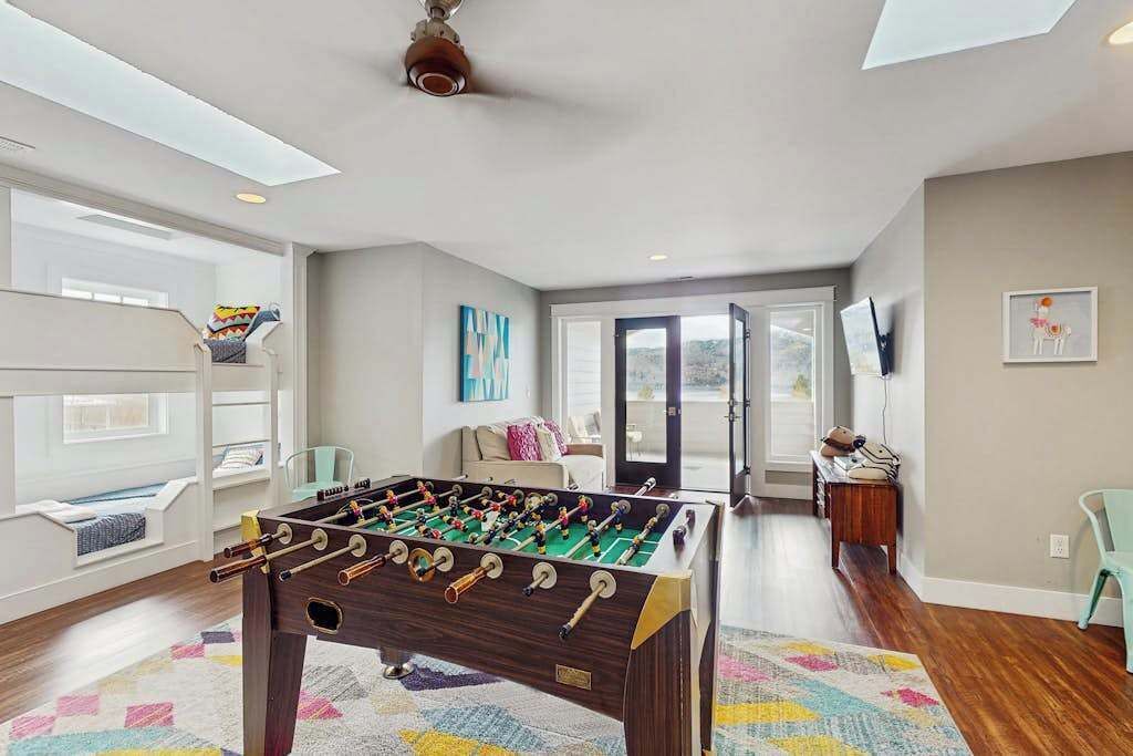 A room with a foosball table, a sofa, a window, and a door leading to another room.