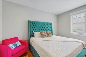 A bedroom with a teal upholstered headboard, a white bedspread, and a red armchair. - Luxury home - wine country - private pool, hot tub (Manson)