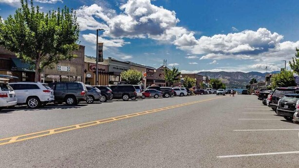 A parking lot with multiple cars, buildings, and a clear sky. - Stylish 1BR Lakefront - Patio - Pool (Chelan)