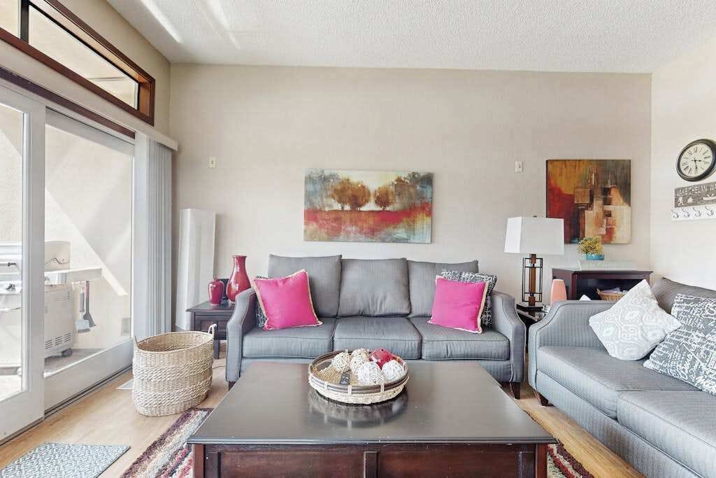 A living room with a grey sofa, a coffee table, and a painting on the wall.