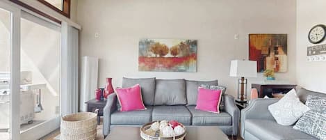 A living room with a grey sofa, a coffee table, and a painting on the wall.