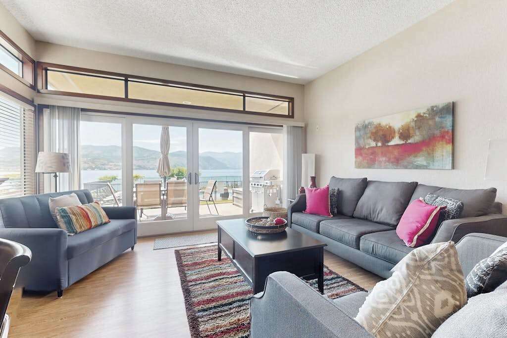 Una sala de estar moderna con un conjunto de sofás, una mesa de centro y un ventanal con vistas al exterior.