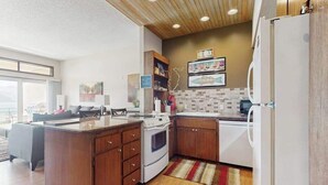 A modern kitchen with wooden cabinets, a central island, and a white refrigerator. - Stylish 1BR Lakefront - Patio - Pool (Chelan)