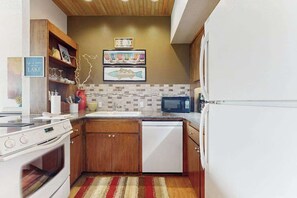 A kitchen with wooden cabinets, a white dishwasher, a microwave, and a stove. - Stylish 1BR Lakefront - Patio - Pool (Chelan)