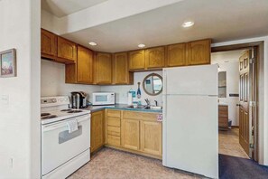 Una cocina con armarios de madera, un refrigerador blanco, un microondas y una estufa.