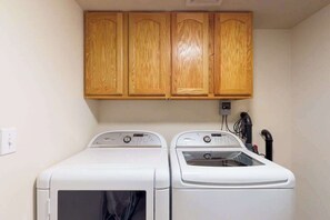Un cuarto de lavandería con dos lavadoras blancas y armarios de madera arriba.