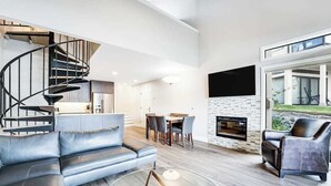 Ein modernes Wohnzimmer mit einer geschwungenen Treppe, einem Kamin und einem Essbereich.