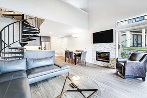 Ein modernes Wohnzimmer mit einer geschwungenen Treppe, einem Kamin und einem Essbereich.