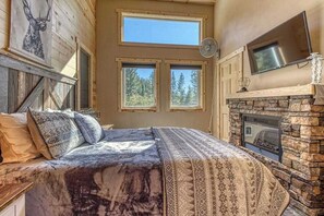 A bedroom with a bed, a fireplace, and a large window. - Woodland 3BR Mountainview Dog Friendly - Hot Tub (Leavenworth)