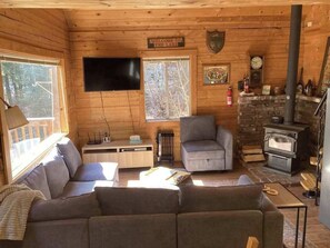 Ein Urlaubsdomizil mit einer Couch, Sesseln, Kamin, Fernseher und einer Willkommensschild.
