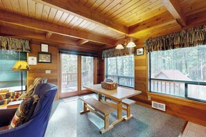 A wooden cabin interior with a sofa, a table, and large windows. - Cozy 2BR Mountainview Dog Friendly Getaway (Leavenworth)