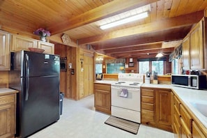 Une cuisine avec des meubles de rangement en bois, un réfrigérateur, une cuisinière et un four à micro-ondes.