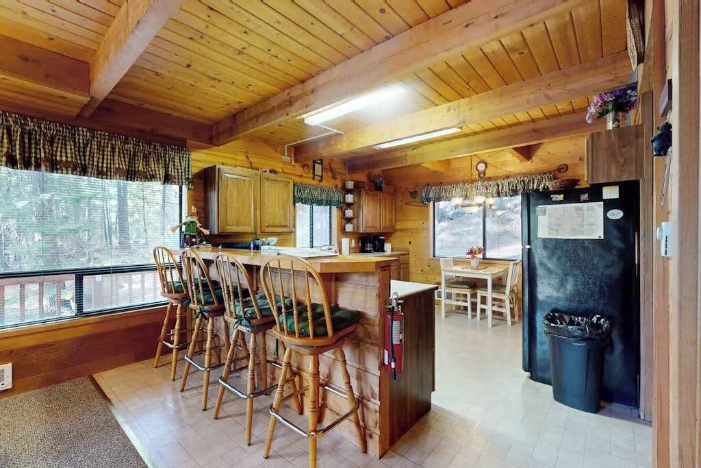A cabin interior with a kitchen area, dining table, and bar seating.
