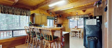 A cabin interior with a kitchen area, dining table, and bar seating.