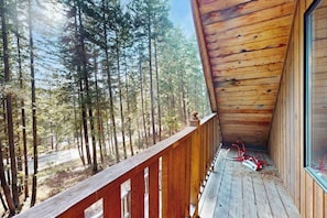 Un balcon en bois donnant sur une forêt.