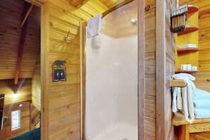 A wooden interior with a shower, towel rack, and a small shelf with toiletries. - Cozy 2BR Mountainview Dog Friendly Getaway (Leavenworth)