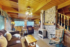 A cozy cabin interior with a stone fireplace, wooden furniture, and a dining area. - Cozy 2BR Mountainview Dog Friendly Getaway (Leavenworth)