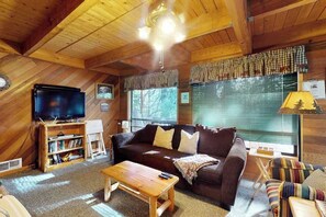 A cozy cabin interior with a wooden ceiling, a television, a sofa, and a window with blinds. - Cozy 2BR Mountainview Dog Friendly Getaway (Leavenworth)