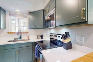 Una cocina moderna con horno empotrado, microondas y bloque de cuchillos.