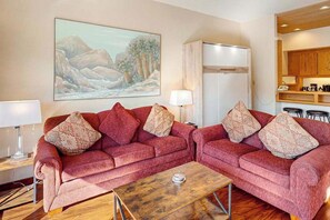 Ein Wohnzimmer mit zwei roten Sofas, einem Couchtisch und einem Bild an der Wand.
