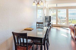 Un coin repas comprenant une table en verre, des chaises, un téléviseur et un canapé.