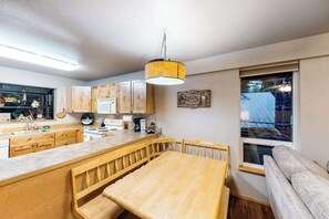 A modern kitchen with wooden cabinets, a central island, and a dining area with a bench. - Woodland 2BR Mountainview Dog Friendly - Deck (Leavenworth)