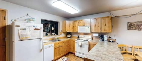 A kitchen with wooden cabinets, a white refrigerator, a stove, and a microwave.