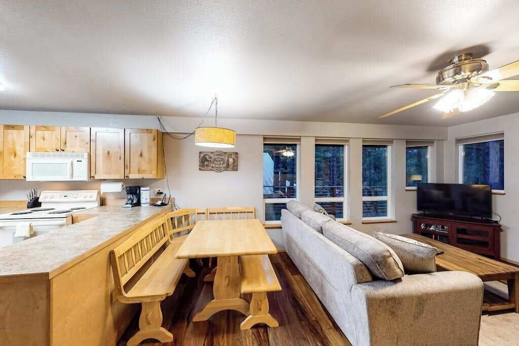 Une cuisine moderne avec des meubles en bois, un coin repas comprenant un banc, un canapé et un téléviseur.
