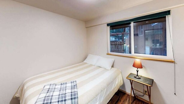 A small, single-bed room with a window, a bedside table with a lamp, and a ceiling light. - Woodland 2BR Mountainview Dog Friendly - Deck (Leavenworth)