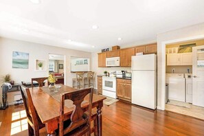 A spacious kitchen with wooden cabinets, a white refrigerator, and a dining area with a wooden table and chairs.