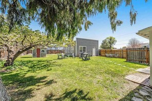 A backyard with a wooden deck, a small shed, and a house with a gray exterior.