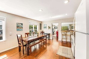 A spacious dining area with a wooden table and chairs, a kitchen area with a refrigerator, and a view through a glass door. - 3BR Lakeview Dog Friendly - Patio - W&D (Manson)