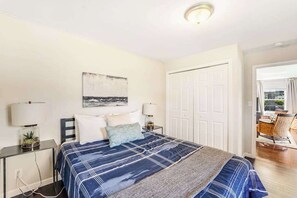 A bedroom with a bed, bedside tables, a painting, and a door leading to a balcony. - 3BR Lakeview Dog Friendly - Patio - W&D (Manson)
